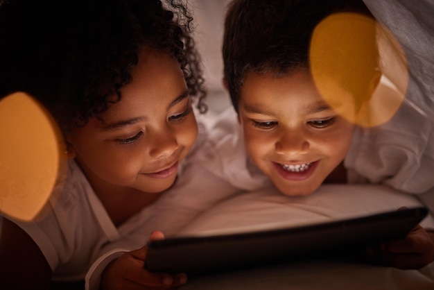 Duas Meninas No Sofá à Noite Com Um Tablet Digital. Jogos