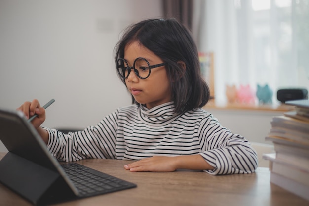 Foto crianças asiáticas bonitas usando um computador portátil estudando através de um sistema de e-learning on-line