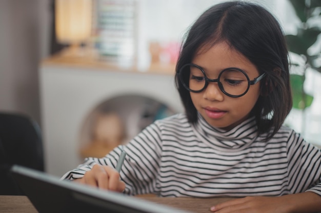 Foto crianças asiáticas bonitas usando um computador portátil estudando através de um sistema de e-learning on-line