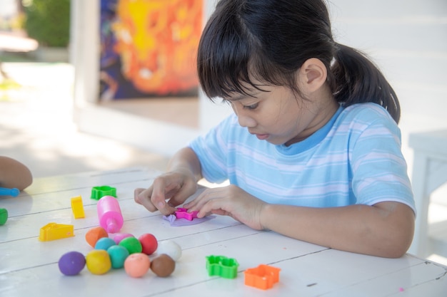 Crianças asiáticas brincam com formas de moldagem de argila, aprendendo brincando