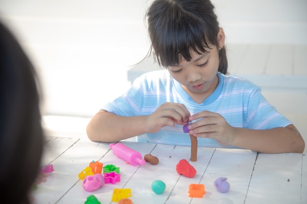 Crianças asiáticas brincam com formas de moldagem de argila, aprendendo brincando