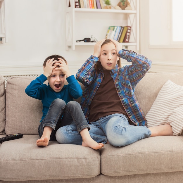 Crianças assustadas assistindo tv em casa