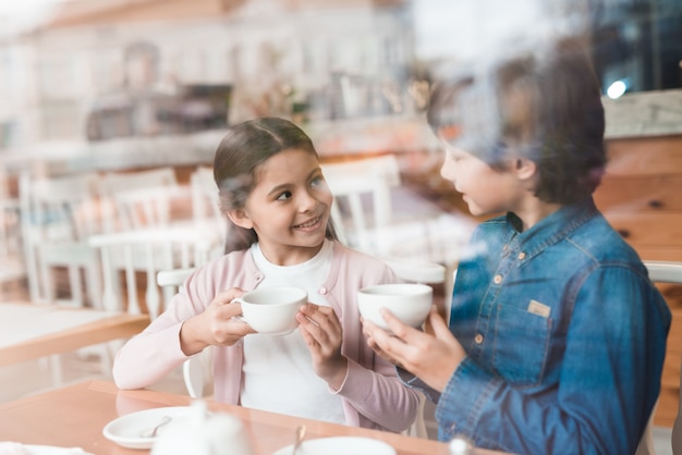 Crianças bebem chá e conversam no café.