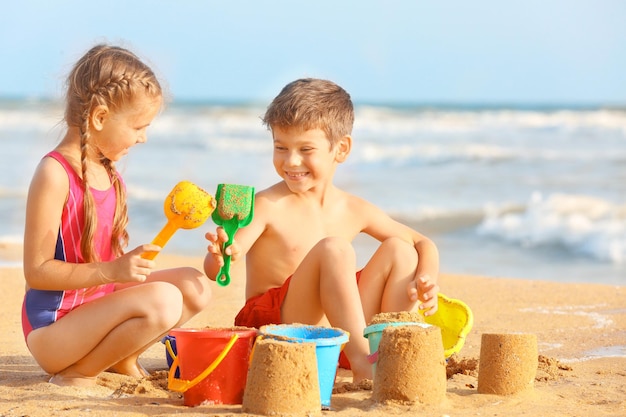 Crianças bonitas a brincar com areia na praia.