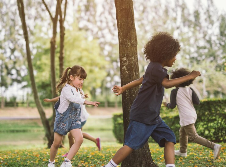 Foto crianças bonitas brincando em torno de árvores no parque