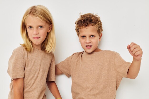 Crianças bonitas e elegantes em camisetas bege posando para se divertir na infância inalterada