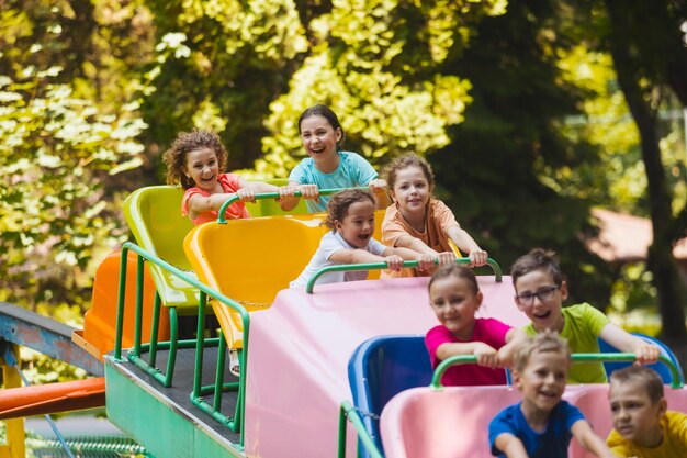 Foto crianças bonitas sentadas num parque de diversões.