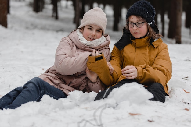 Crianças brincam na floresta de neve Crianças ao ar livre no inverno Amigos brincando na neve férias de Natal para família com crianças pequenas