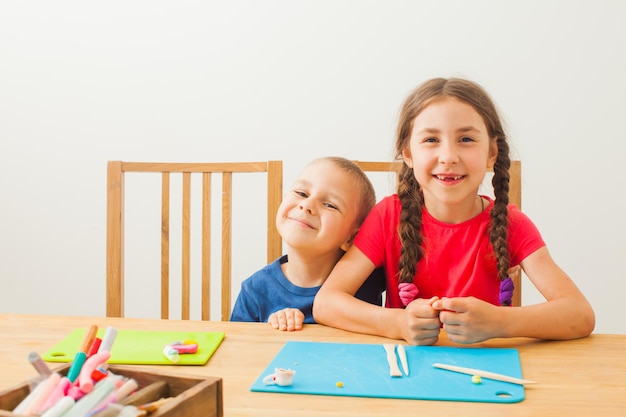 Crianças brincando com argila colorida na mesa