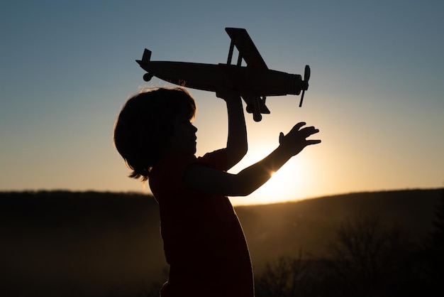 Crianças brincando com avião de madeira vintage ao ar livre retrato de crianças contra o fundo do céu pôr do sol de verão conceito de viagem e liberdade rosto de crianças fofas