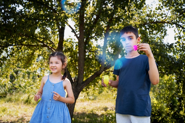 Foto crianças brincando com bolhas de sabão ao ar livre na natureza