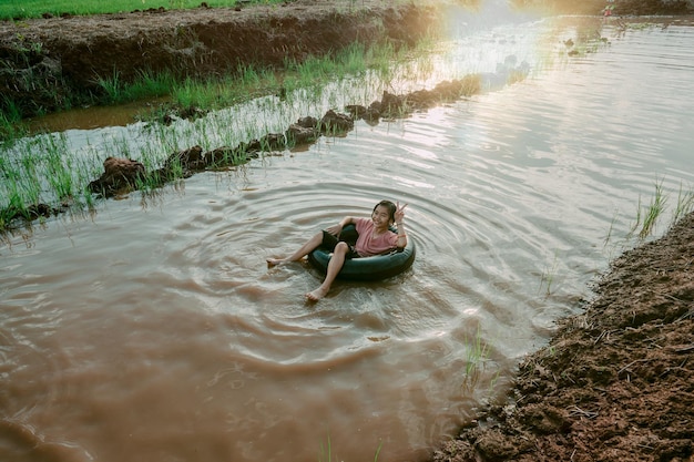 Crianças brincando e nadando no canal da fazenda orgânica na zona rural