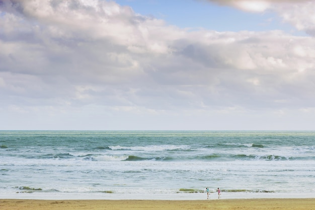 Crianças brincando na praia sob o céu nublado da manhã