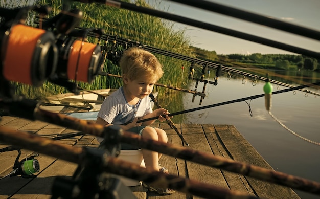 Crianças brincando - um jogo feliz. Garotinho adorável pescando em uma doca de madeira no lago