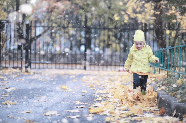 Crianças caminham no parque com a primeira neve