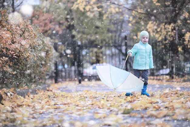 Crianças caminham no parque com a primeira neve