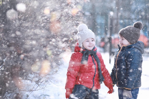 Crianças caminham no parque com a primeira neve