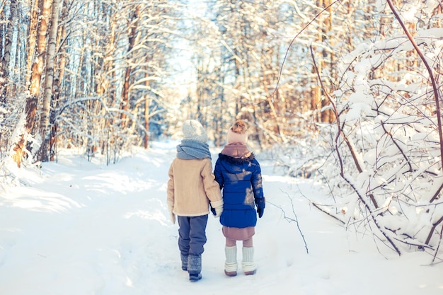 Foto crianças caminham numa floresta coberta de neve no inverno