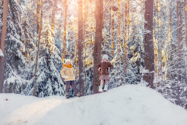 Crianças caminham numa floresta coberta de neve no inverno