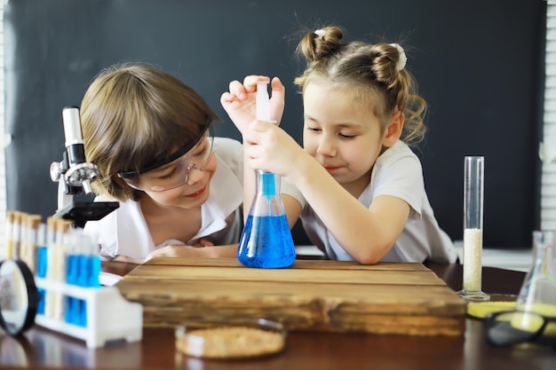 Crianças cientistas Crianças em idade escolar no laboratório realizam experimentos Meninos e meninas com um microscópio