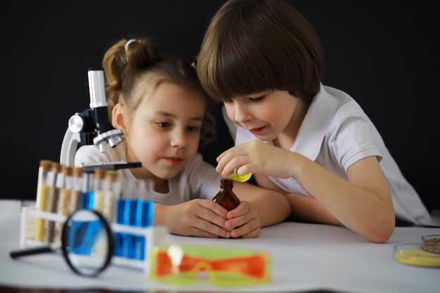 Crianças cientistas Crianças em idade escolar no laboratório realizam experimentos Meninos e meninas com um microscópio