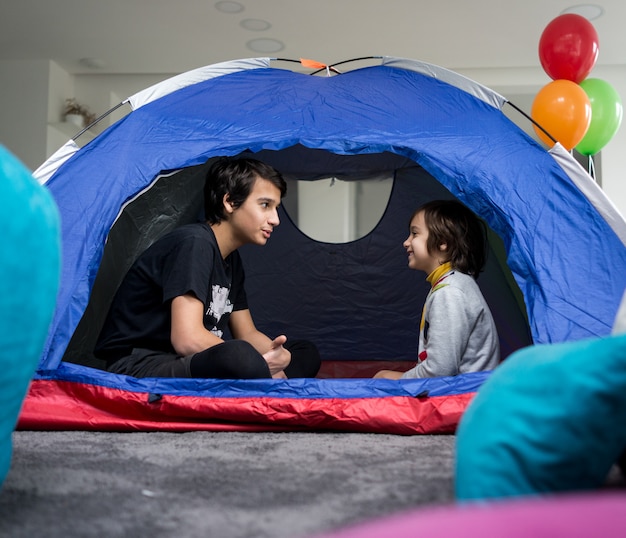 Crianças com barraca de acampamento na sala de diversão e aventura