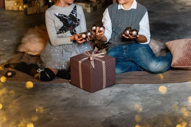 Foto crianças com bolas douradas e presentes.