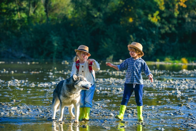 Crianças com cachorro no parque ensolarado de verão perto da água Verão no campo Lazer de verão