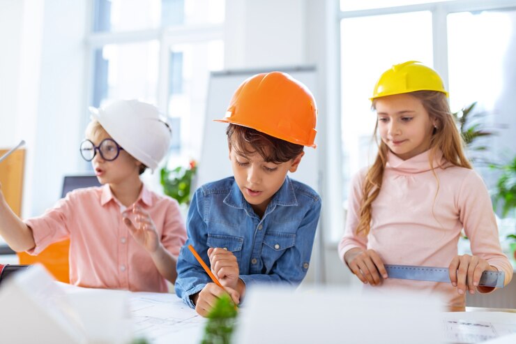 Foto crianças com capacetes. alunos usando capacetes sentindo-se alegres enquanto fazem esboços de construção