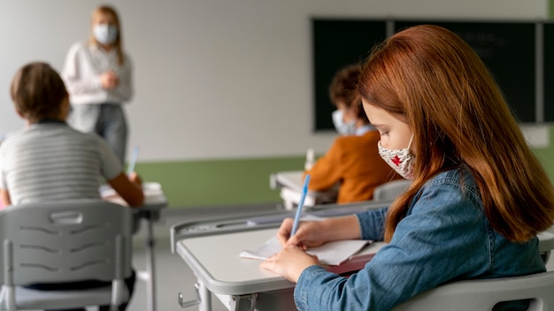 Foto crianças com máscaras médicas frequentando a escola