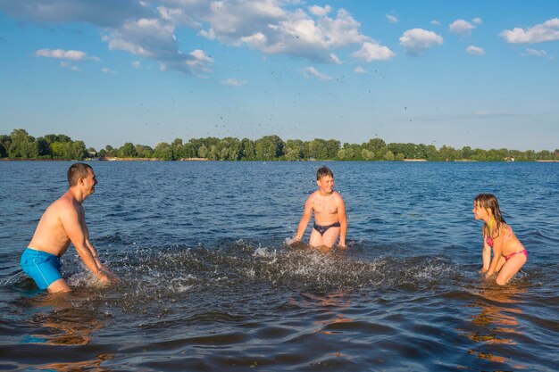 Crianças com o pai estão brincando no rio Jogos em família nas férias Estilo de vida de descanso ativo