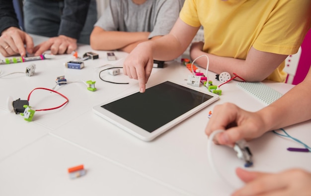 Crianças com tablet estudando robótica na escola