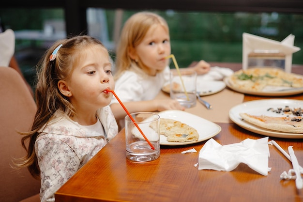 Crianças comendo em um restaurante com canudos e copos