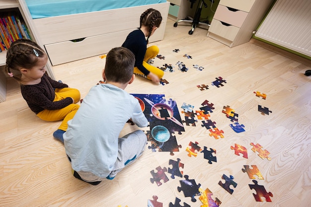 Crianças conectando peças de quebra-cabeça em um quarto infantil no chão em casa Lazer divertido para a família