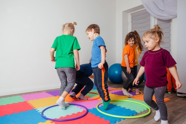 Crianças correndo e pulando em aros multicoloridos no chão