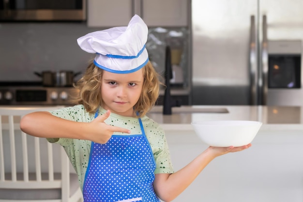 Crianças cozinhando na cozinha Garoto engraçado chef cozinha culinária na cozinha Garoto garoto fazendo comida saudável Retrato de criança com chapéu de chef