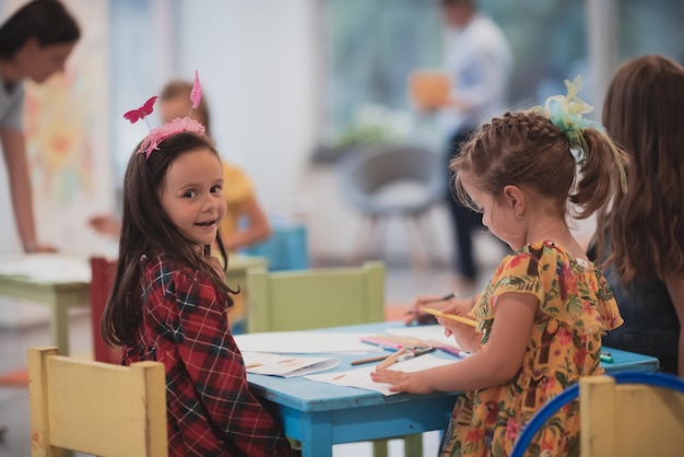 Crianças criativas sentadas em uma instituição pré-escolar desenham e se divertem enquanto recebem educação