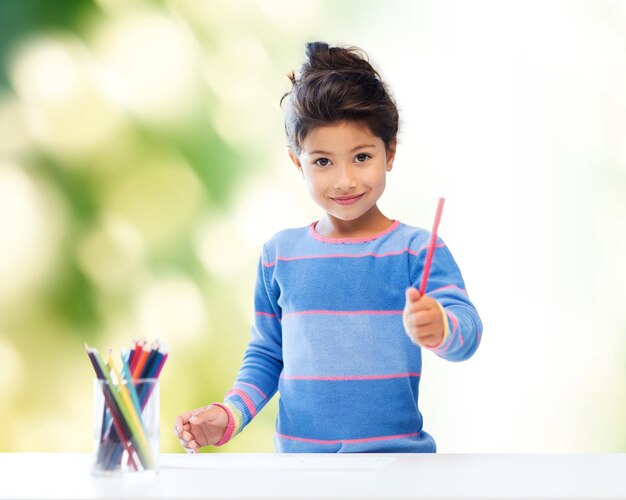 crianças, criatividade e conceito de pessoas felizes - menina feliz desenhando com lápis de cor sobre fundo verde