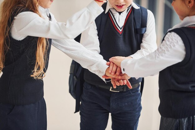 Crianças da escola de uniforme fazendo gesto de vitória juntos no corredor Concepção de educação