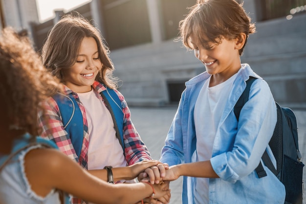 Crianças da escola estão de mãos dadas no quintal