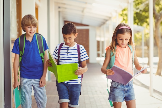 Crianças da escola lendo livros enquanto caminhava no corredor