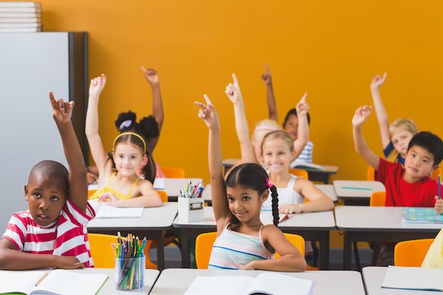 Crianças da escola levantando a mão na sala de aula