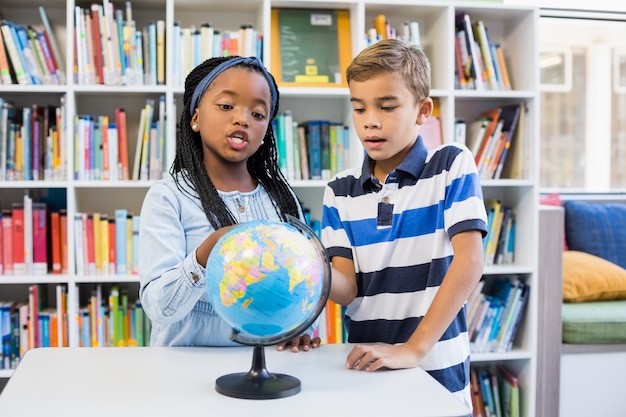 Crianças da escola olhando o globo na biblioteca