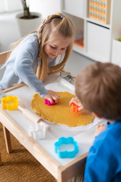 Foto crianças de alto ângulo fazendo biscoitos juntos