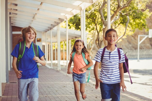 Crianças de escola feliz correndo no corredor