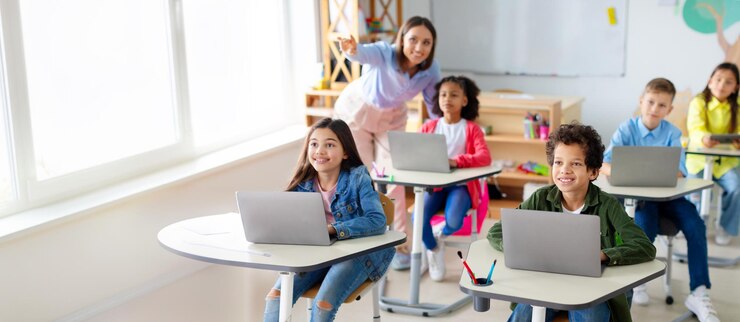 Foto crianças de escola usando laptops professora apontando para o quadro durante o teste de exame no computador