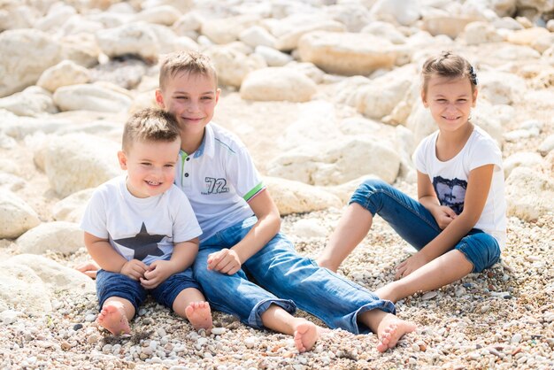 Crianças de família felizes em pé sobre um pontão de madeira em frente ao mar no verão.