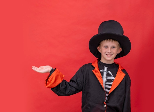 Crianças de Halloween, um menino em uma fantasia de esqueleto segura um jack o lanterna vermelho espaço de cópia de fundo uma criança