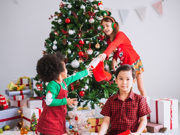 Crianças de muitas nacionalidades comemoram o dia de natal, crianças sob a árvore de natal com caixas de presente