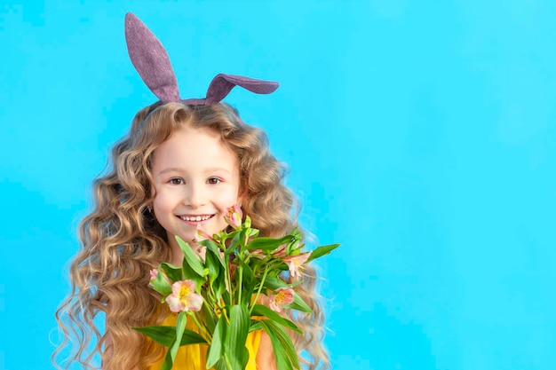 Crianças de páscoa de férias garota sorridente com orelhas de coelho lebre de coelho flores de primavera em azul
